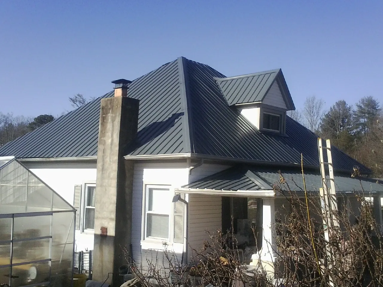 Dark blue standing seam metal roof on a white farmhouse with dormer — Slate & Tile Roof Repair by Roofing Brothers in Rickreall