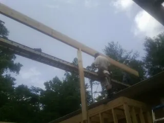 Carpenter setting a ridge beam over a new addition frame — Ice Dam Removal by Roofing Brothers in Rickreall