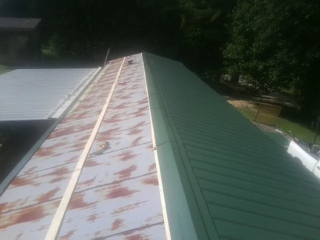 Old rusted panels beside newly installed green metal roofing — Wind Damage Roof Repair by Roofing Brothers in Rickreall