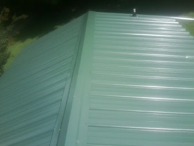 New green metal panels meeting at the ridge of a roof — Flat Roof Repair work by our crew in Rickreall