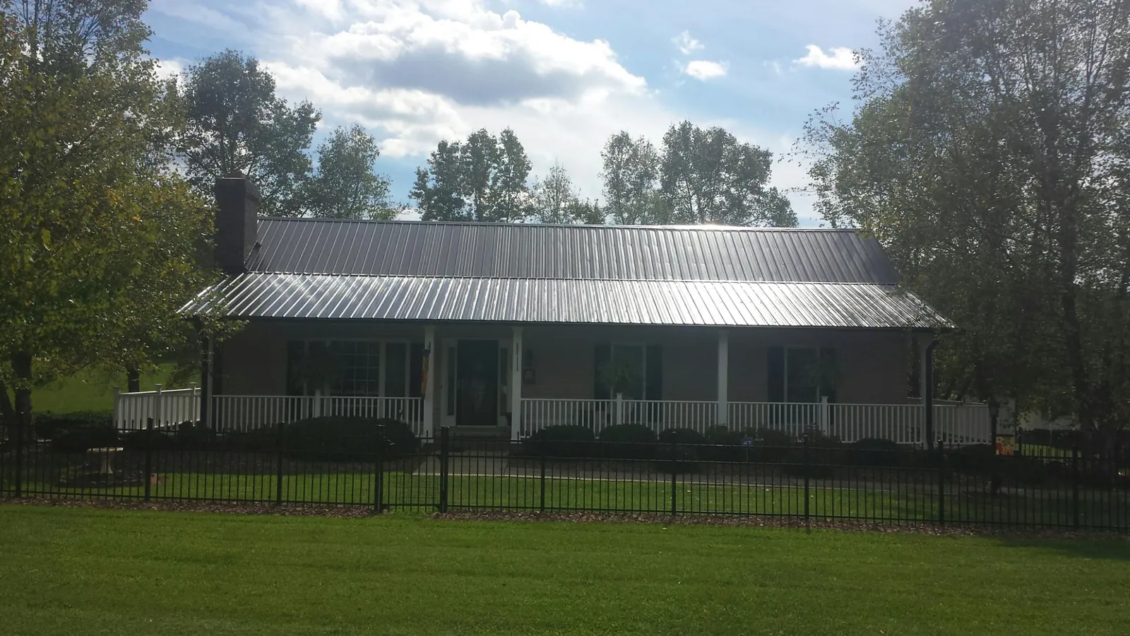 Gray metal roof on a brick ranch with a full width front porch — Gutter Guard Installation work by our crew in Rickreall