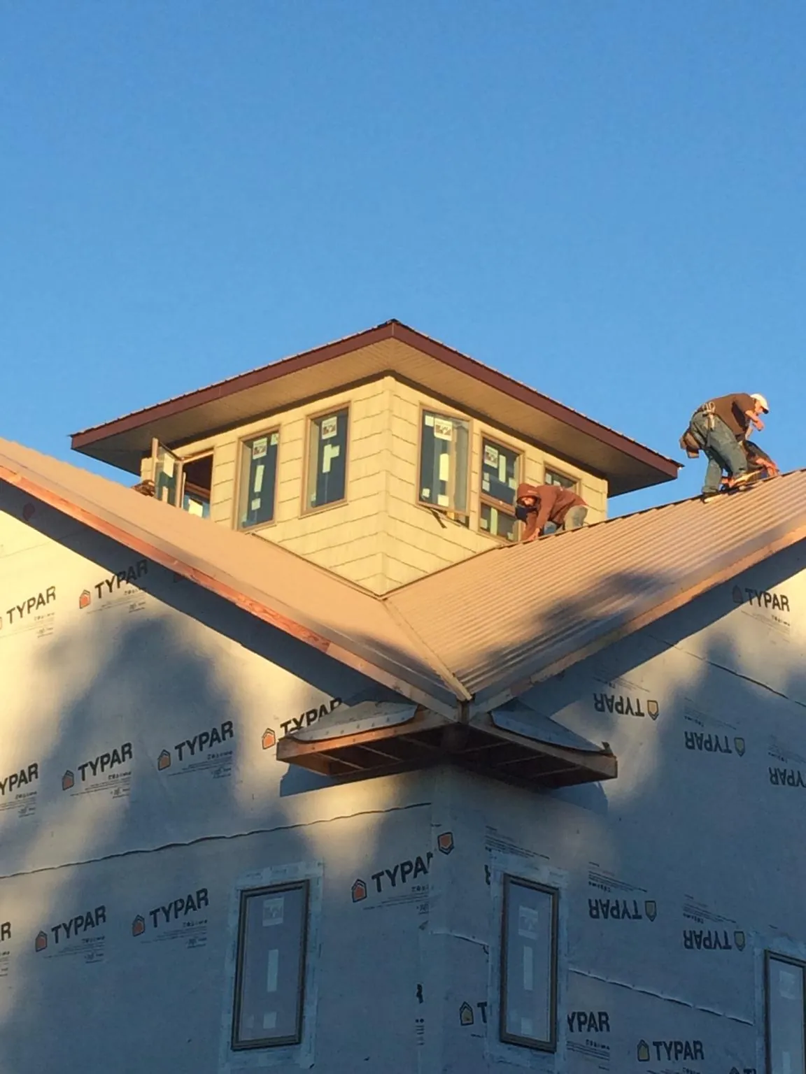Roofers working around a rooftop cupola on a new metal roof at sunset — Roof Waterproofing in Rickreall by Roofing Brothers